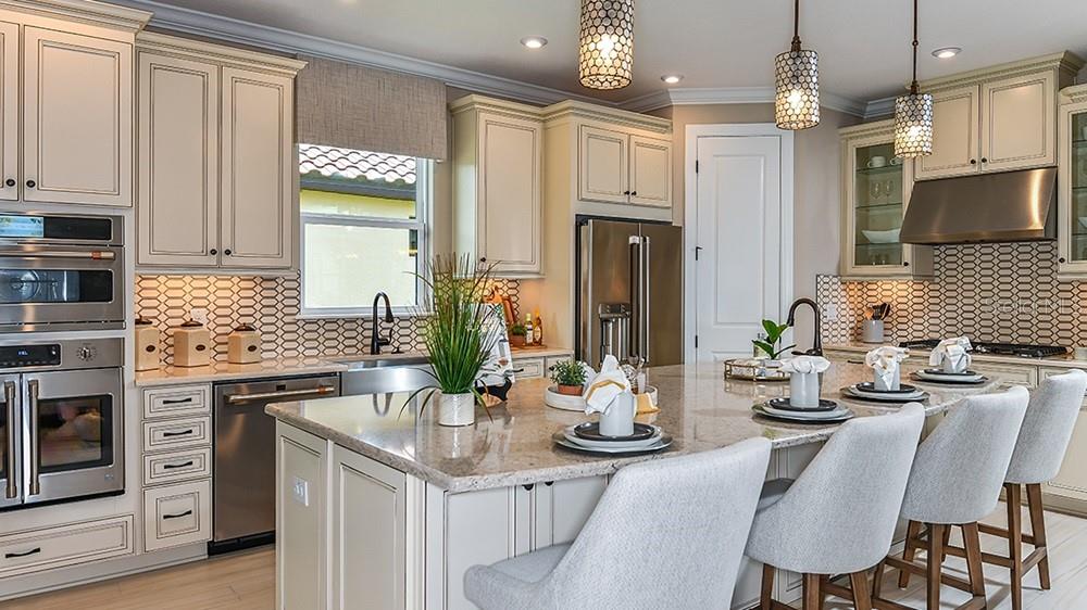 A kitchen with cream cabinets, a large granite island, stainless steel appliances, and pendant lighting — 30189 IMPERATI BOULEVARD, WESLEY CHAPEL, FL