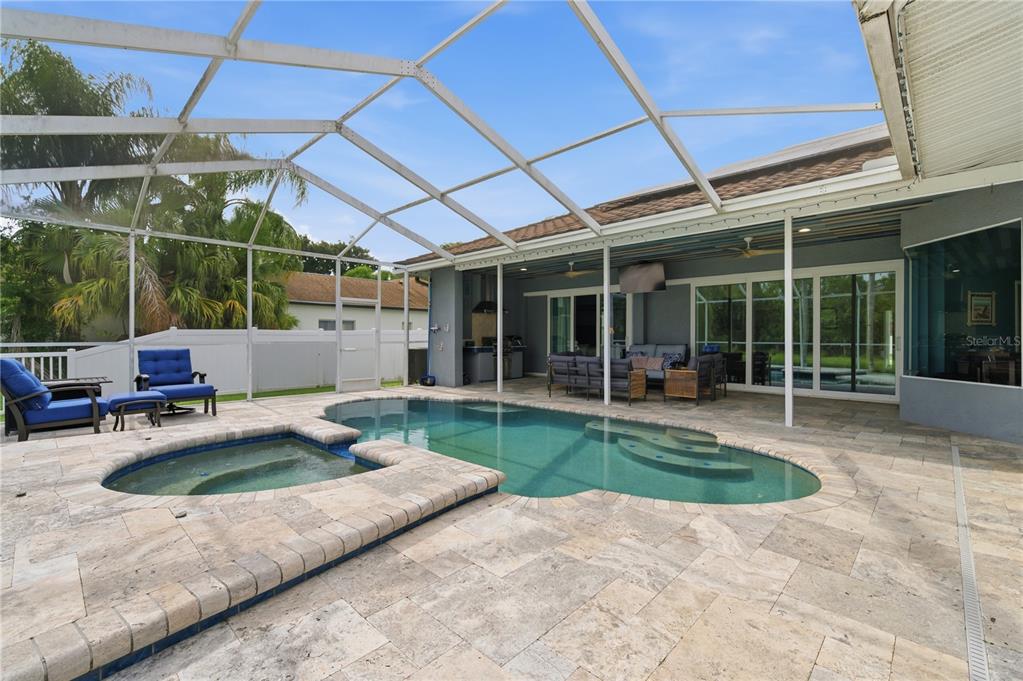 A bright kitchen with white cabinets and an island overlooks a living room and patio — 17024 WINNERS CIRCLE, ODESSA, FL