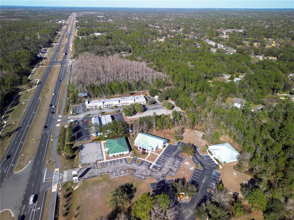 An aerial view shows several commercial buildings with parking lots situated next to a highway — 8427 S SUNCOAST BOULEVARD, HOMOSASSA, FL