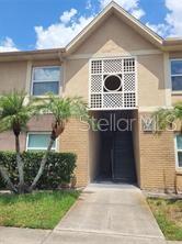 A two-story tan building with a central entryway, decorative lattice panel, and palm trees — 9911 TURF COURT UNIT 2, ORLANDO, FL