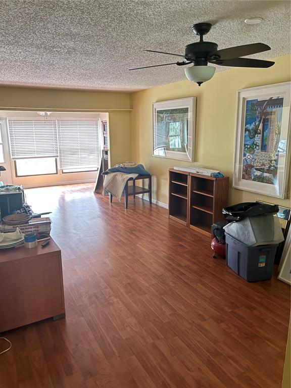 A living room with wood-look flooring, a ceiling fan, and two framed wall art pieces — 2968 FLINT DRIVE S, CLEARWATER, FL