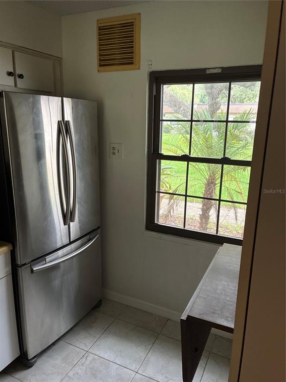 A kitchen corner features a stainless steel refrigerator, a window, and a small table — 2968 FLINT DRIVE S, CLEARWATER, FL