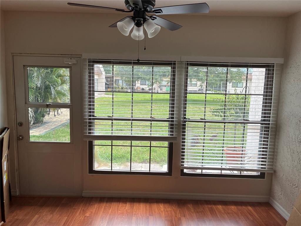A room with wood-look flooring, a ceiling fan, and windows overlooking a grassy yard — 2968 FLINT DRIVE S, CLEARWATER, FL