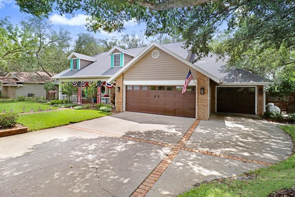 A suburban house features a two-car garage, a front porch, and a concrete driveway — 1976 DUNLOE CIRCLE, DUNEDIN, FL