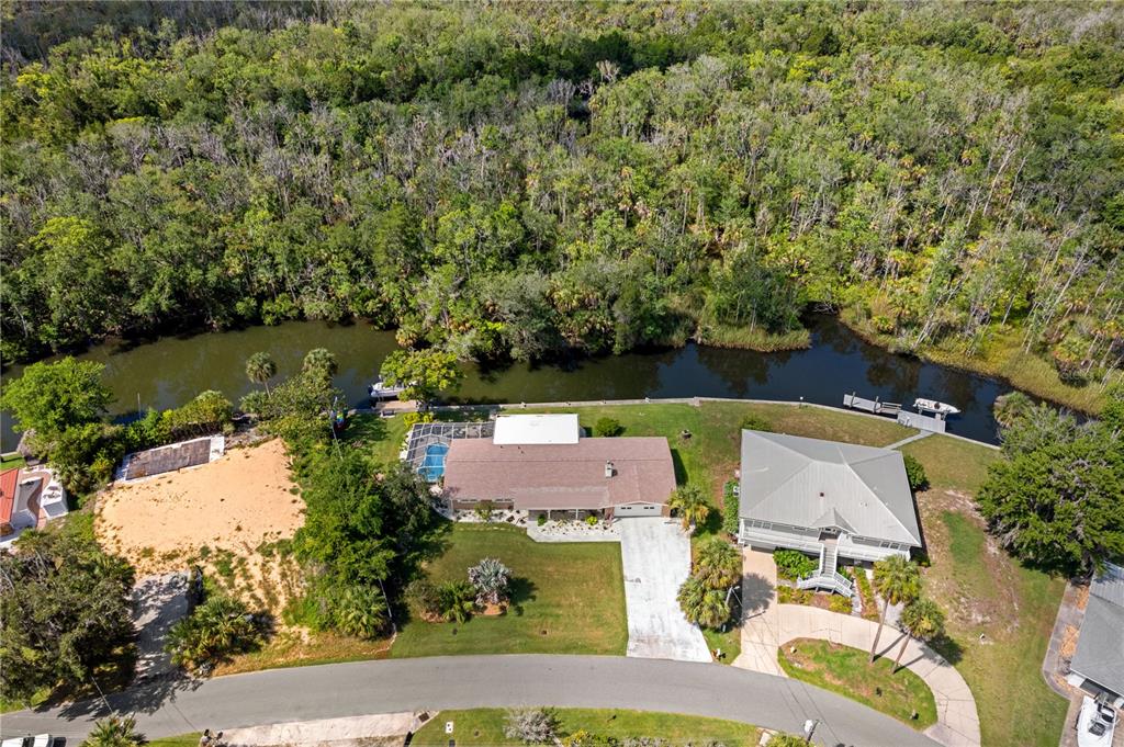 An aerial view shows two waterfront houses with docks along a canal near a forest — 2160 N WATERSEDGE DRIVE, CRYSTAL RIVER, FL