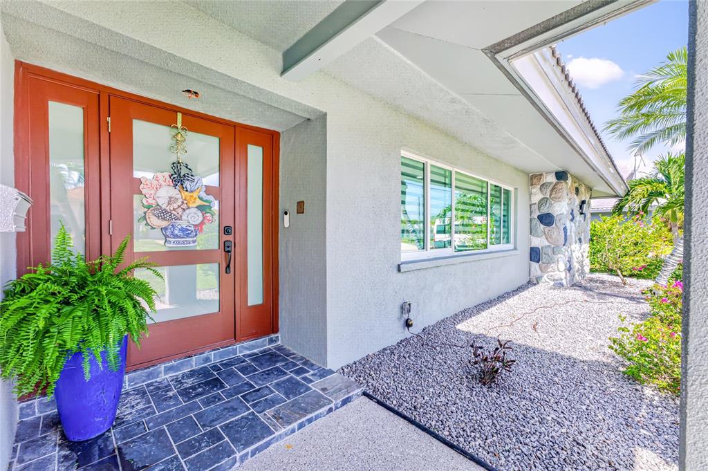 The exterior front entrance features a red door, a blue planter, and a gravel garden — 321 CAPRI ISLES CT, PUNTA GORDA, FL