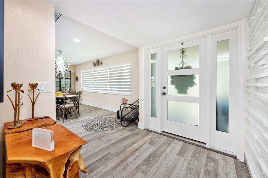 An entryway with wood-look flooring, a white front door with glass panels, and a dining area — 321 CAPRI ISLES CT, PUNTA GORDA, FL