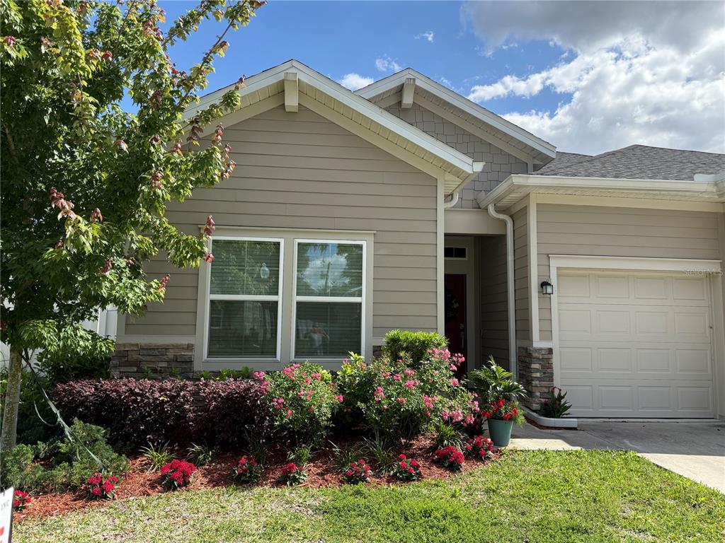 A tan house exterior features a front-facing gable, a garage, and a landscaped front yard — 7656 SW 74TH LOOP, OCALA, FL