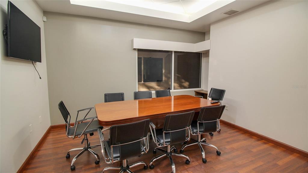 A conference room features a wooden table, black chairs, and a television on the wall — 8865 COMMODITY CIRCLE UNIT 106, ORLANDO, FL