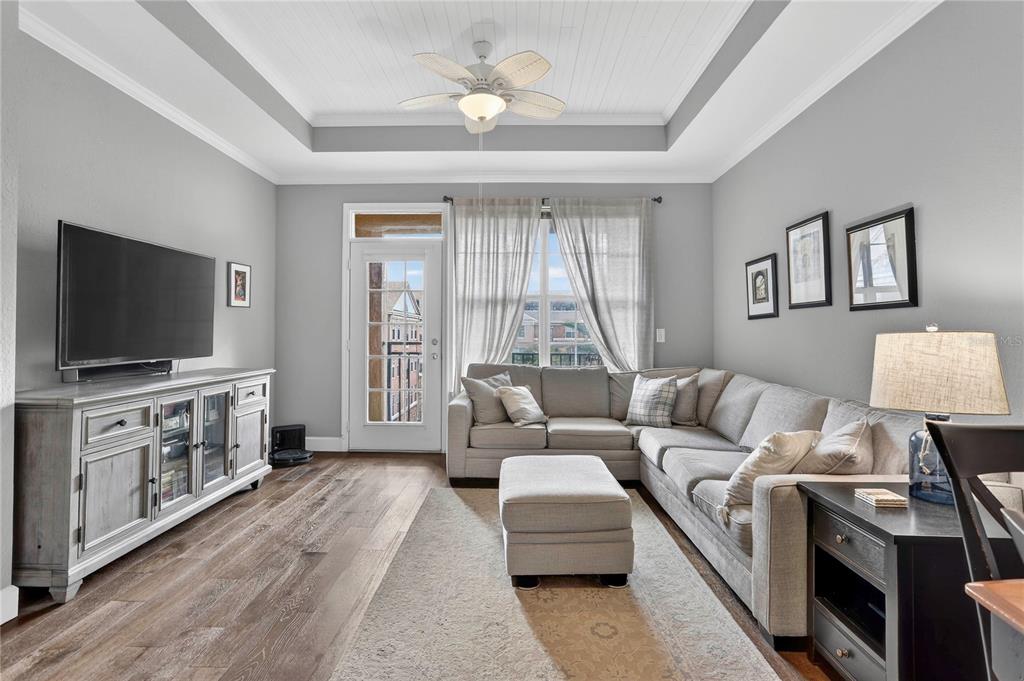 A living room features a grey sectional sofa, a television console, and a tray ceiling — 4221 W SPRUCE STREET UNIT 2426, TAMPA, FL