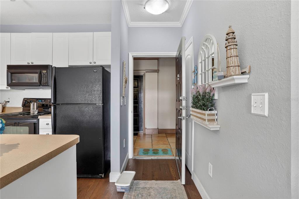 A kitchen with a black refrigerator and microwave opens into a hallway with tiled flooring — 4221 W SPRUCE STREET UNIT 2426, TAMPA, FL