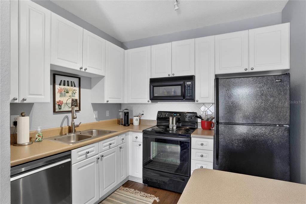 A kitchen features white cabinets, black appliances, a double sink, and tan countertops — 4221 W SPRUCE STREET UNIT 2426, TAMPA, FL