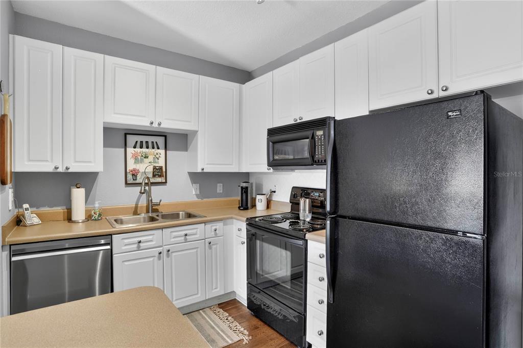 A kitchen features white cabinets, black appliances, a stainless steel dishwasher, and tan countertops — 4221 W SPRUCE STREET UNIT 2426, TAMPA, FL