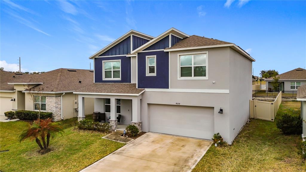 A two-story house with a blue and gray exterior, a front porch, and a garage — 4004 MALAWI TRAIL, ST CLOUD, FL