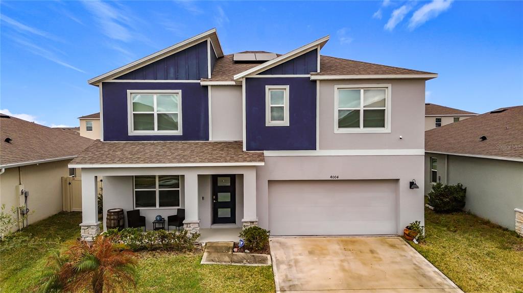 A two-story house features a blue and beige exterior with a front porch and garage — 4004 MALAWI TRAIL, ST CLOUD, FL