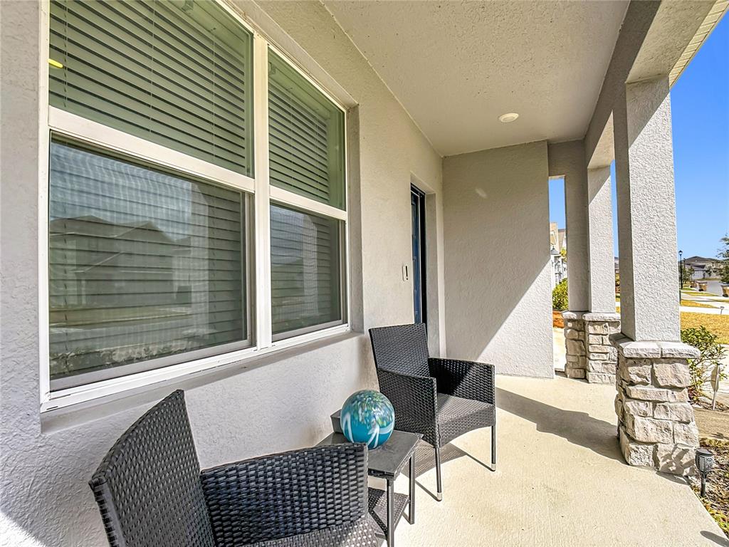 A covered front porch features two wicker chairs, a small table, and stone-based columns — 4004 MALAWI TRAIL, ST CLOUD, FL