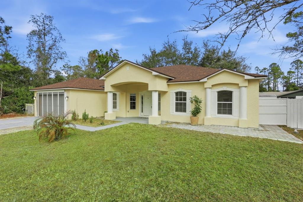 A yellow single-story house with a brown roof, front porch columns, and a paved walkway — 78 PANORAMA, PALM COAST, FL