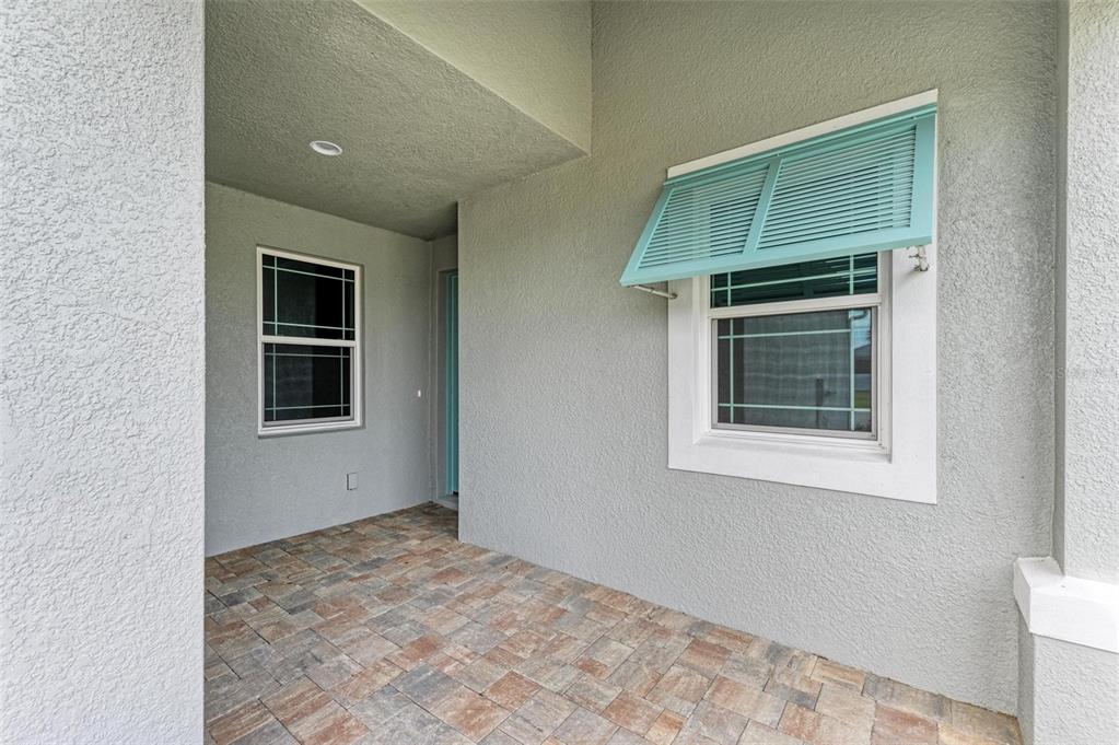 A covered entryway features gray stucco walls, a paver floor, and a window with shutters — 149 OKEEFFE CIRCLE, BRADENTON, FL