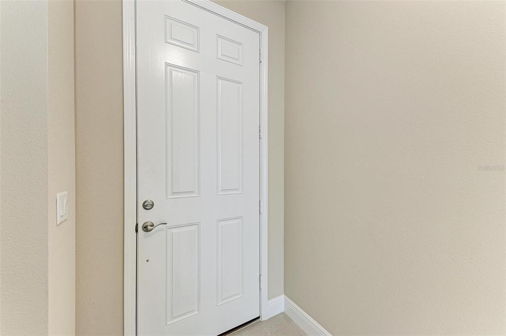 A white six-panel door is set into a beige wall with a light switch nearby — 149 OKEEFFE CIRCLE, BRADENTON, FL