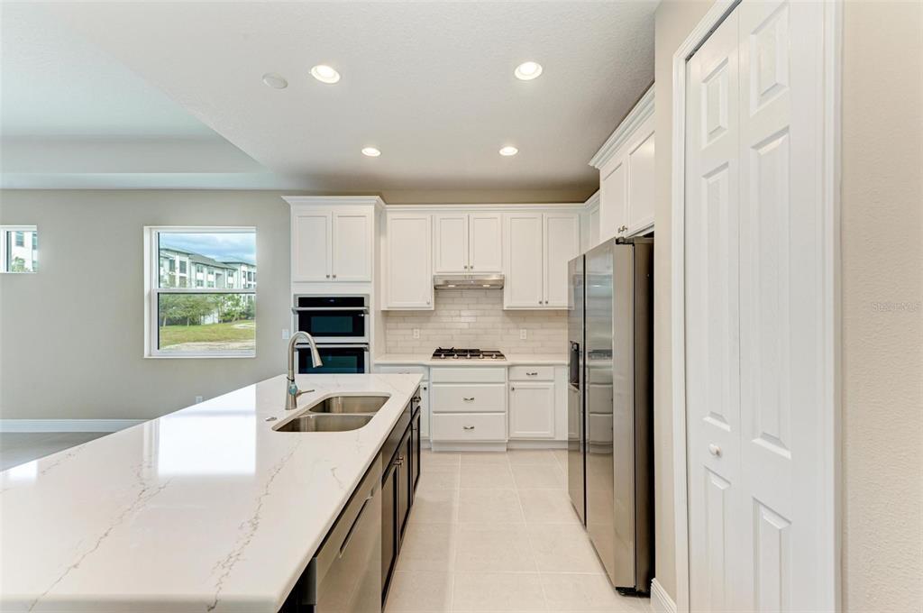 A modern kitchen features white cabinets, a large quartz island, and stainless steel appliances — 149 OKEEFFE CIRCLE, BRADENTON, FL