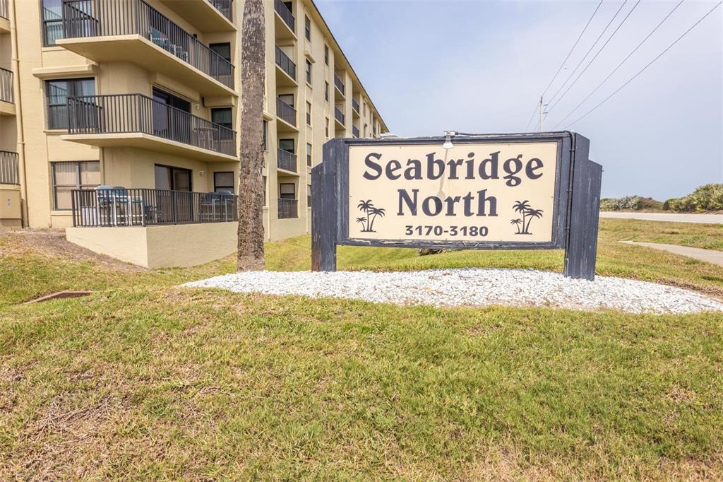A sign for Seabridge North stands on a grassy lawn in front of a multi-story building — 3170 OCEAN SHORE BOULEVARD UNIT 305, ORMOND BEACH, FL