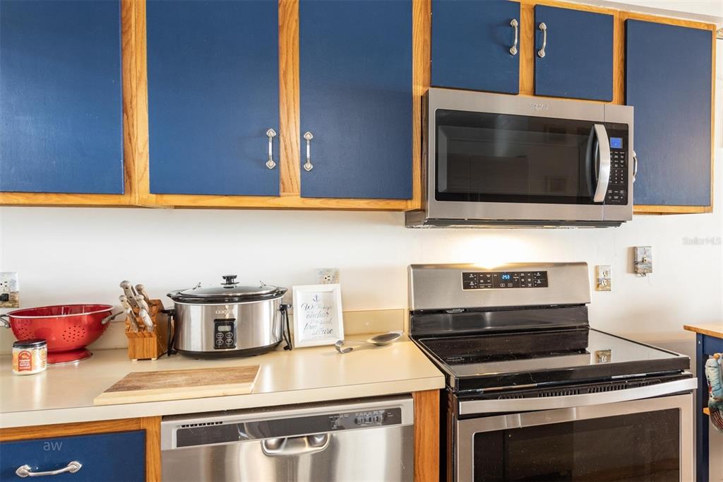 A kitchen features blue cabinets, stainless steel appliances, and a light-colored countertop — 3170 OCEAN SHORE BOULEVARD UNIT 305, ORMOND BEACH, FL