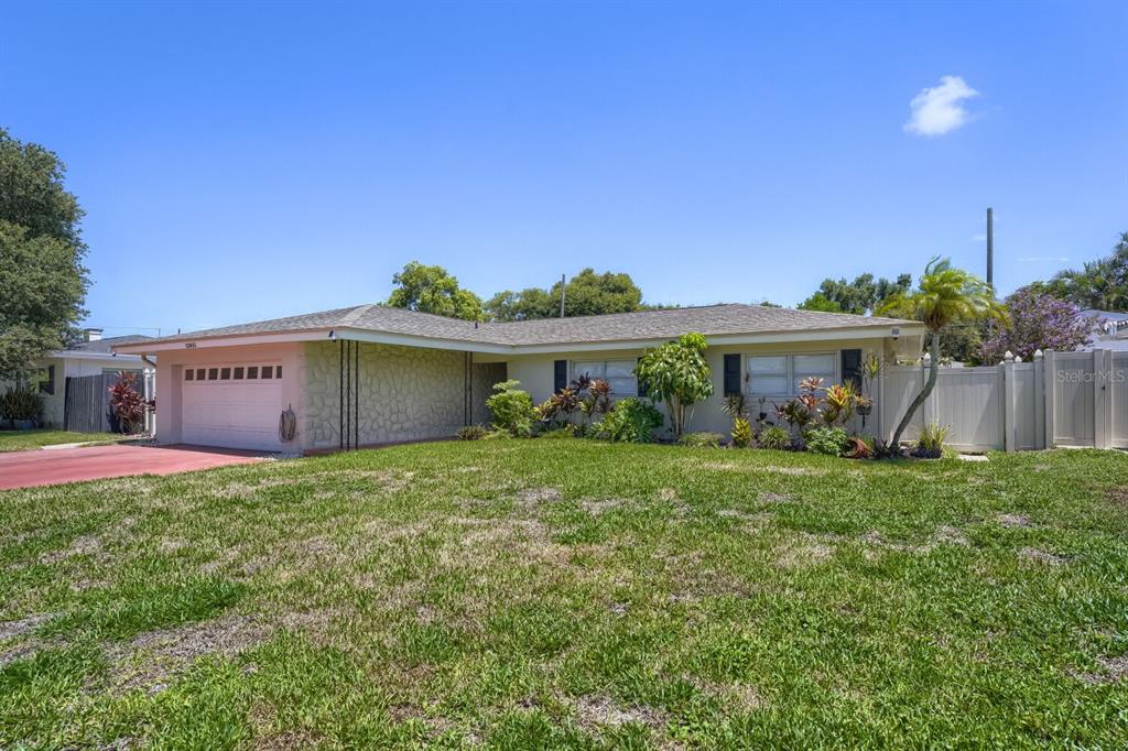 A single-story house with a stone-textured garage wall, a lawn, and a white privacy fence — 13931 DOMINICA DRIVE, SEMINOLE, FL