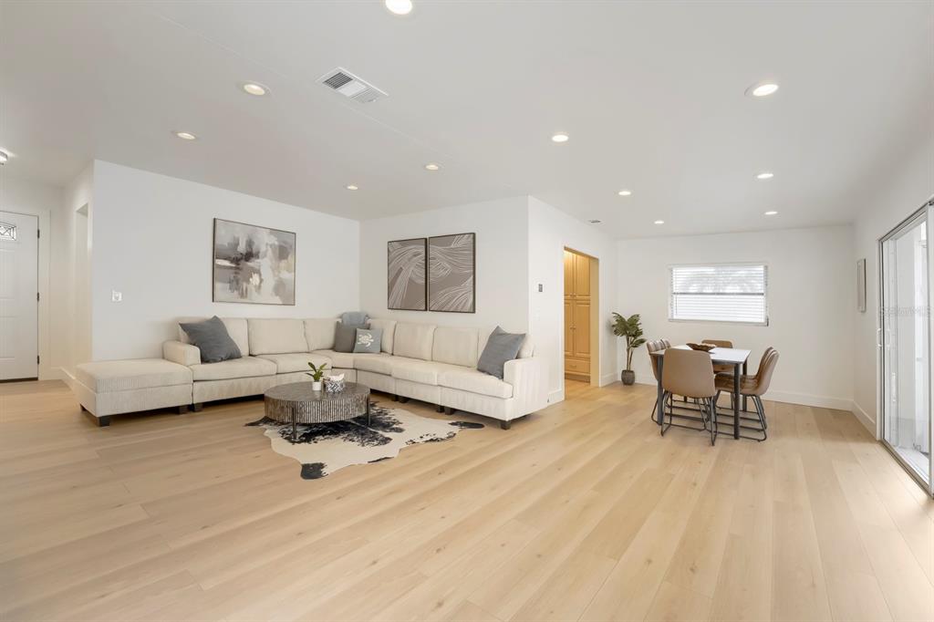 A bright, open-concept living and dining area features light wood flooring and a large sectional — 13931 DOMINICA DRIVE, SEMINOLE, FL