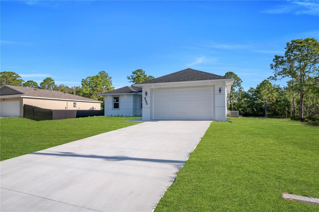 A single-story house with a white exterior, a two-car garage, and a concrete driveway — 1009 MOORE AVENUE, LEHIGH ACRES, FL