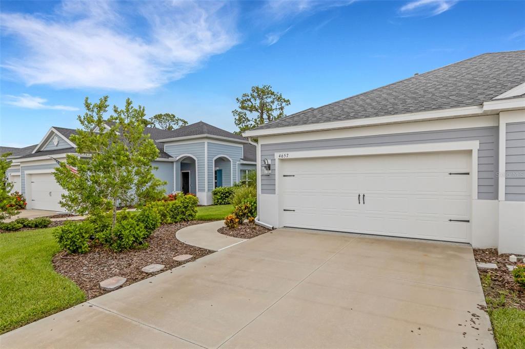A view of a suburban home exterior with a white garage door and driveway — 4657 WILLOW BEND AVENUE, PARRISH, FL