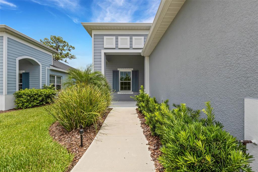 A concrete walkway leads to the covered entryway of a house with gray siding — 4657 WILLOW BEND AVENUE, PARRISH, FL