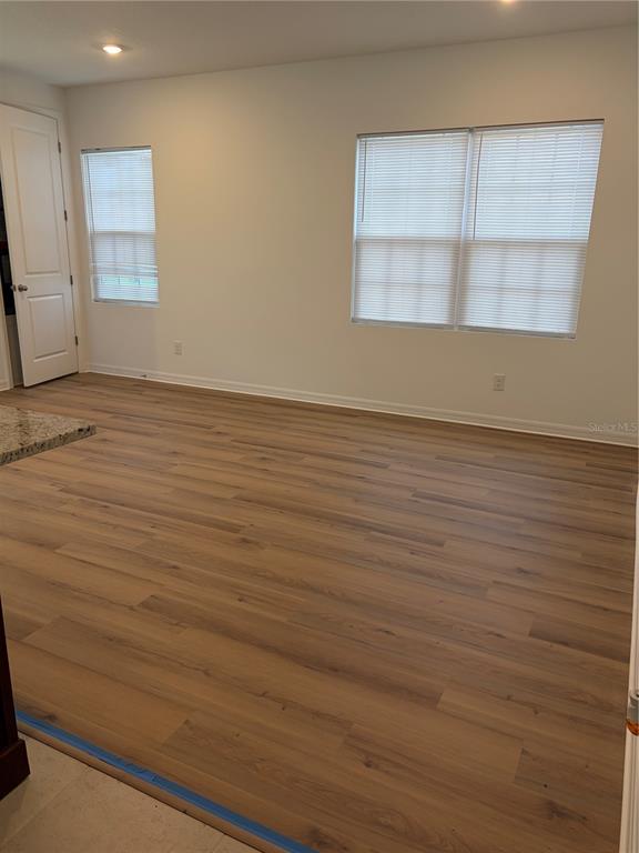An empty room features light wood-look flooring, white walls, and two windows with blinds — 2984 EMBARK TRAIL, ST CLOUD, FL