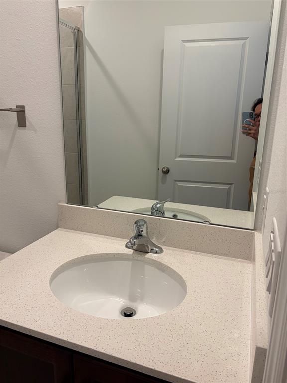 A bathroom vanity features a white speckled countertop, a single sink, and a large mirror — 2984 EMBARK TRAIL, ST CLOUD, FL