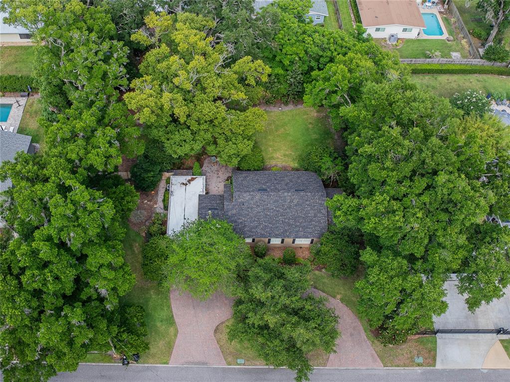 An aerial view shows a house with a dark shingled roof surrounded by mature trees — 2804 NEVADA ROAD, LAKELAND, FL