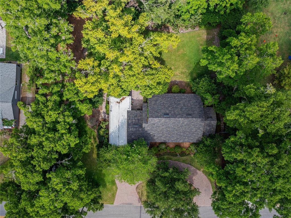 An aerial view shows a house with a shingled roof surrounded by dense green trees — 2804 NEVADA ROAD, LAKELAND, FL