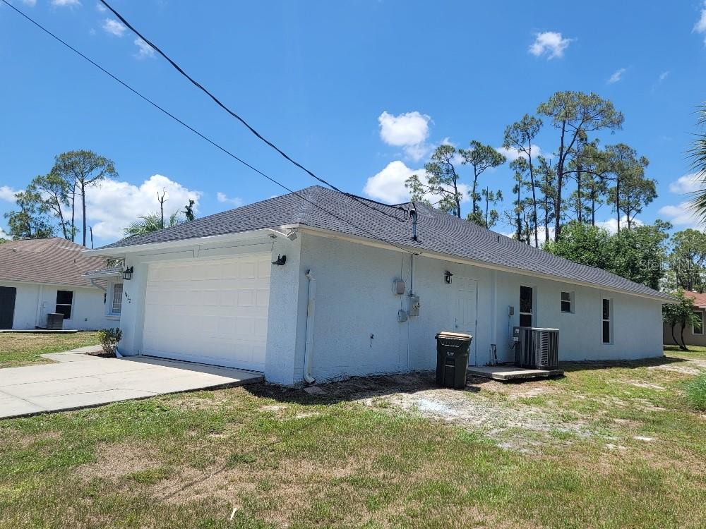 The exterior side and garage of a light blue house under a clear blue sky — 1422 JAKWAY ROAD, NORTH PORT, FL