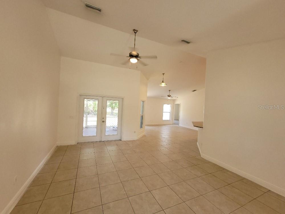 An open-concept living area features light tile flooring, vaulted ceilings, and glass French doors — 1422 JAKWAY ROAD, NORTH PORT, FL