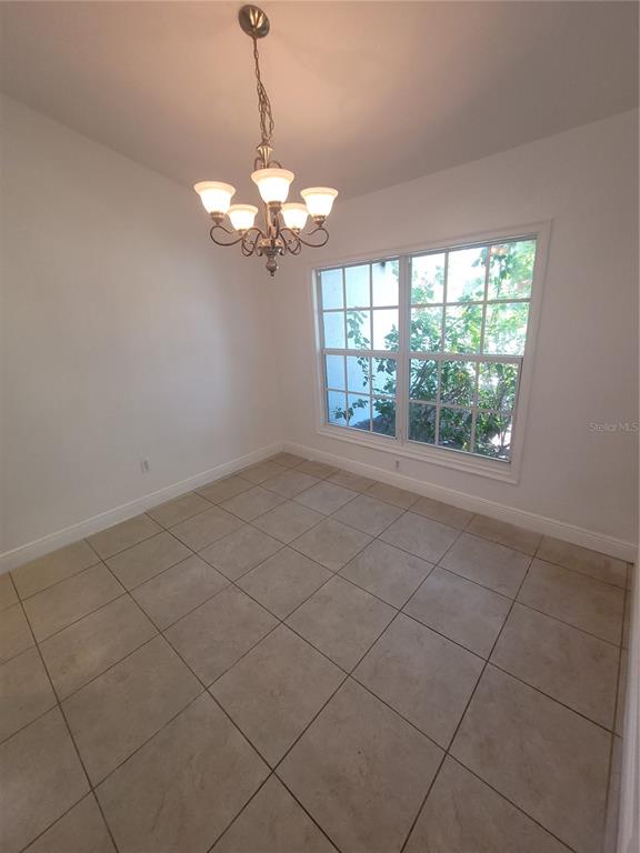 An empty dining room with white walls, tile flooring, a chandelier, and a large window — 1422 JAKWAY ROAD, NORTH PORT, FL