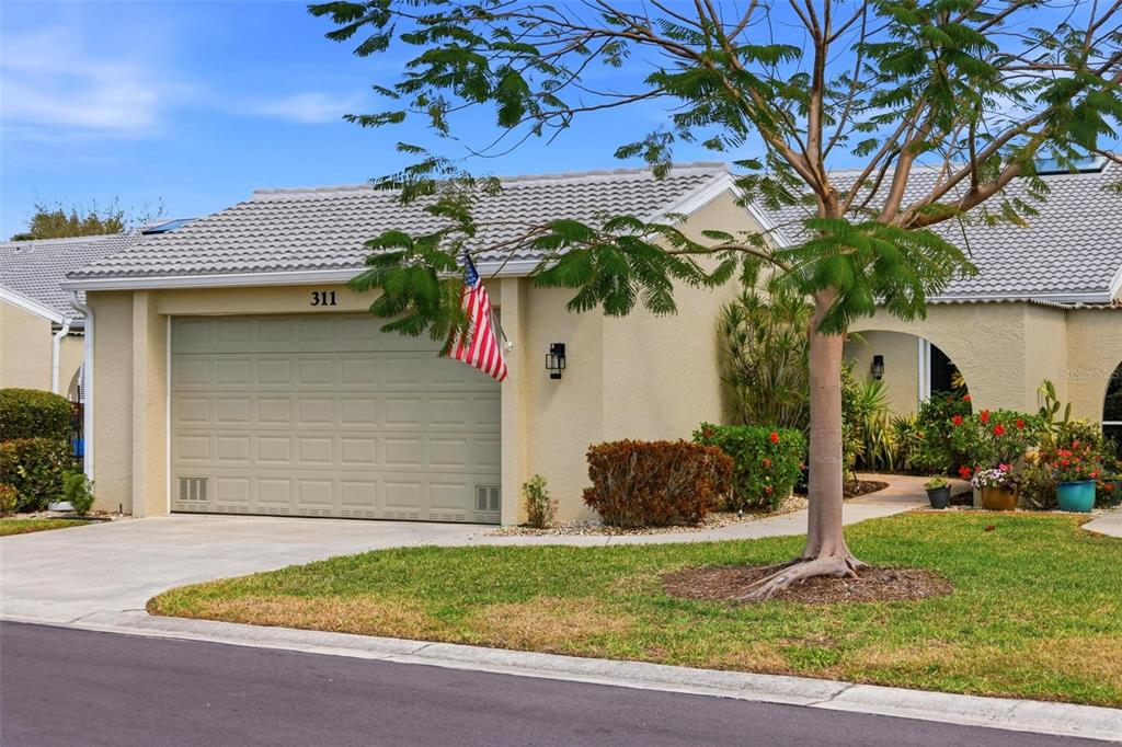 A single-story house with a beige stucco exterior, a two-car garage, and a tiled roof — 2521 W MARION AVENUE UNIT 311, PUNTA GORDA, FL