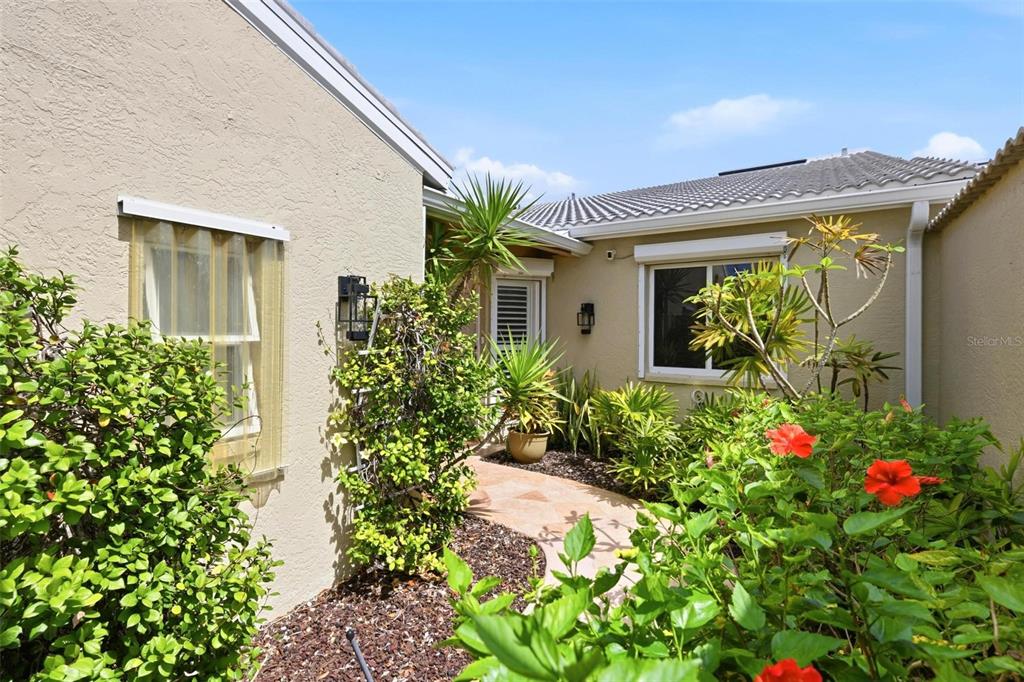 A stone walkway leads to the front entrance of a house surrounded by lush landscaping — 2521 W MARION AVENUE UNIT 311, PUNTA GORDA, FL