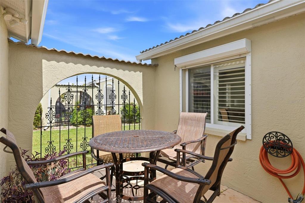 A patio with a round metal table and chairs sits in front of a gated archway — 2521 W MARION AVENUE UNIT 311, PUNTA GORDA, FL