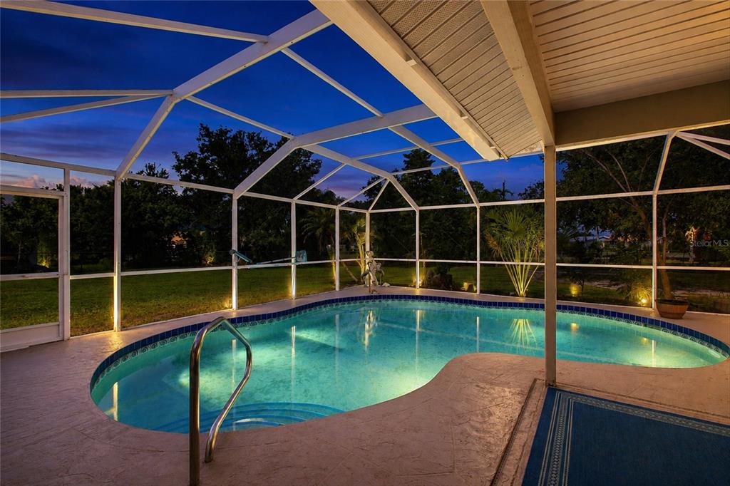 A screened-in swimming pool with a concrete deck at dusk — 5948 JAVA COURT, NORTH PORT, FL