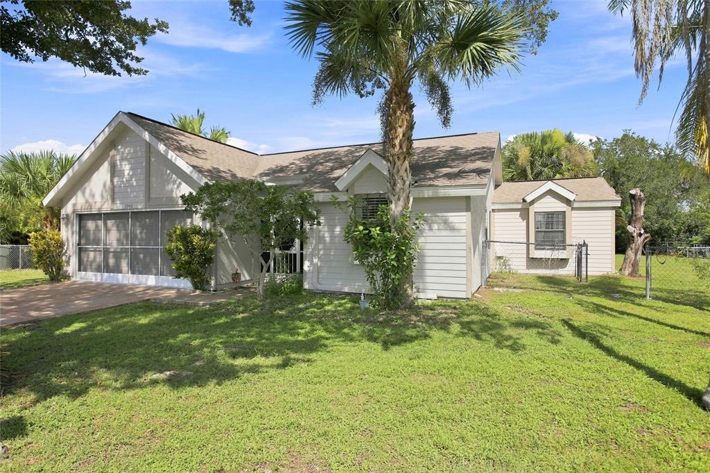 A single-story house with light-colored siding, a screened garage, and a palm tree in front — 5948 JAVA COURT, NORTH PORT, FL