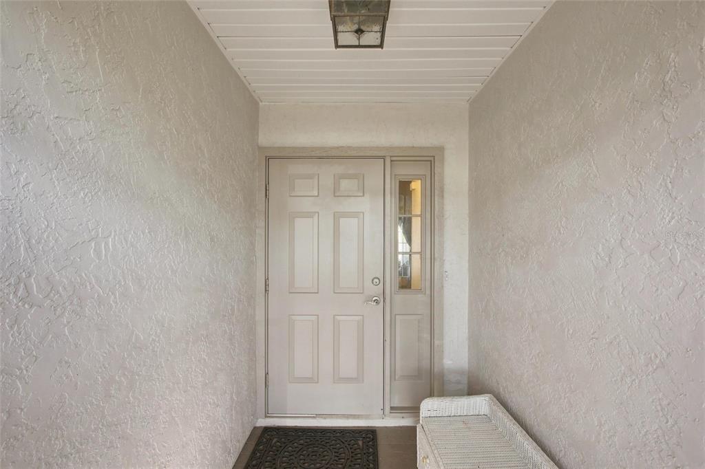 A front entryway features a beige door with a sidelight, textured walls, and a ceiling light — 5948 JAVA COURT, NORTH PORT, FL