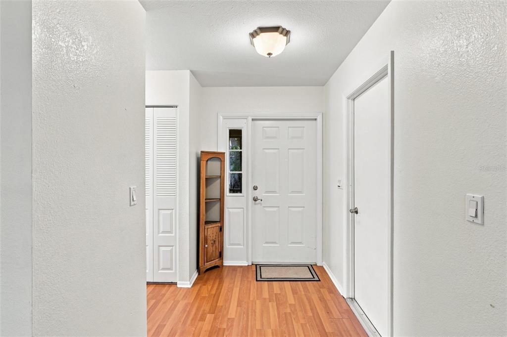 An entryway features wood-look flooring, a white front door with a sidelight, and a corner cabinet — 5948 JAVA COURT, NORTH PORT, FL
