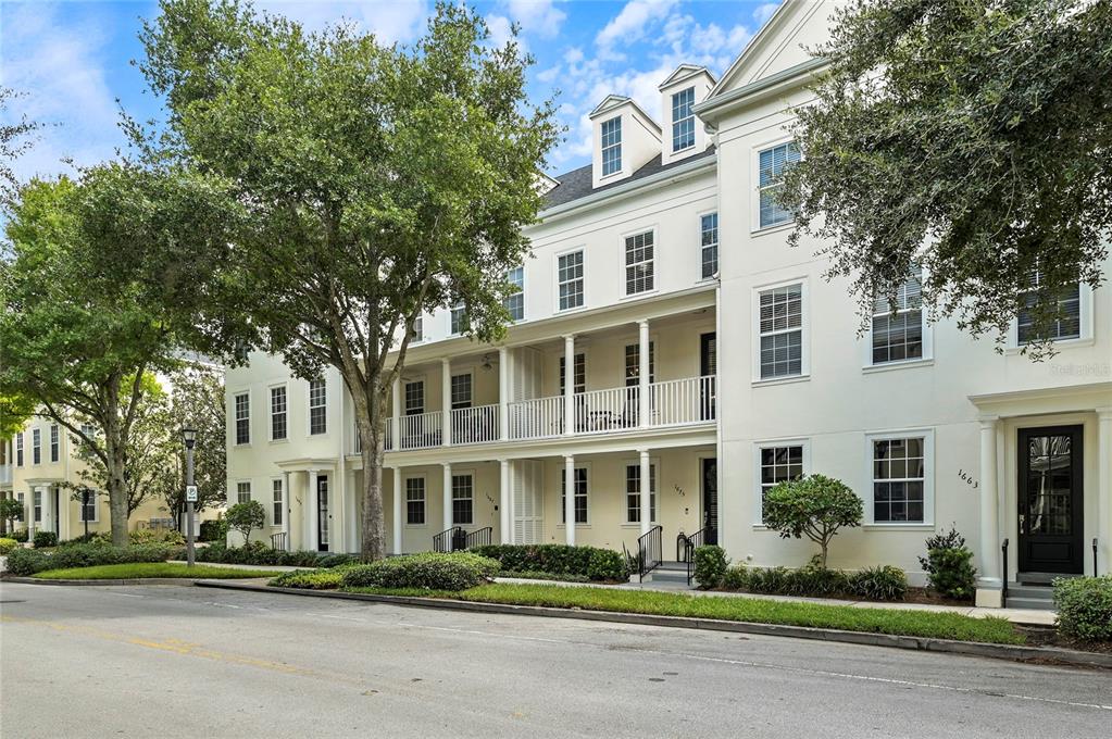 A multi-story white townhouse building features a second-floor balcony and large trees in front — 1675 PROSPECT AVENUE, ORLANDO, FL