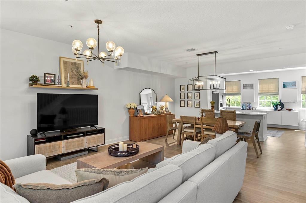 An open-concept living and dining area features light wood flooring, modern light fixtures, and neutral decor — 1675 PROSPECT AVENUE, ORLANDO, FL