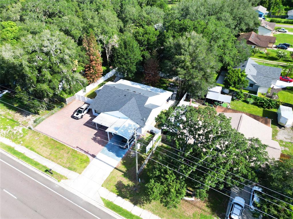An aerial view shows a house with a large driveway, carport, and surrounding trees — 1915 E LAKE DRIVE, CASSELBERRY, FL