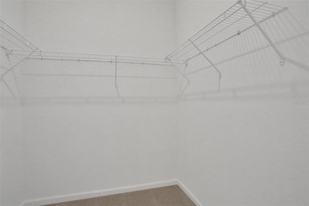 A walk-in closet features white wire shelving mounted on plain white walls above carpeted flooring — 204 DONOVAN DRIVE, ST AUGUSTINE, FL