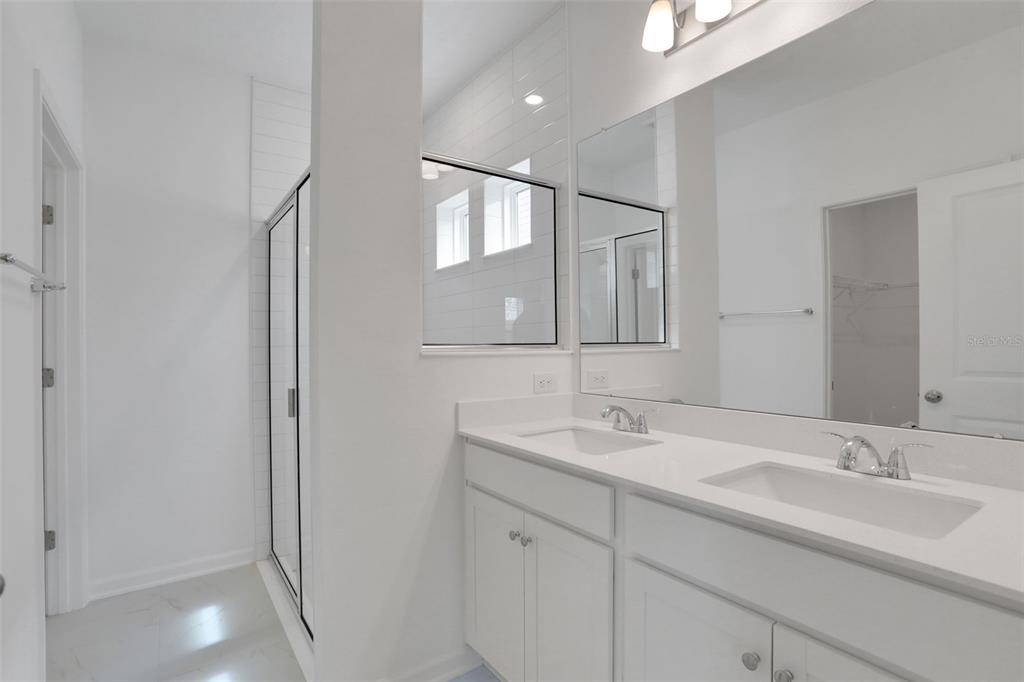 A bright bathroom features a double vanity with white cabinets and a glass-enclosed shower — 204 DONOVAN DRIVE, ST AUGUSTINE, FL
